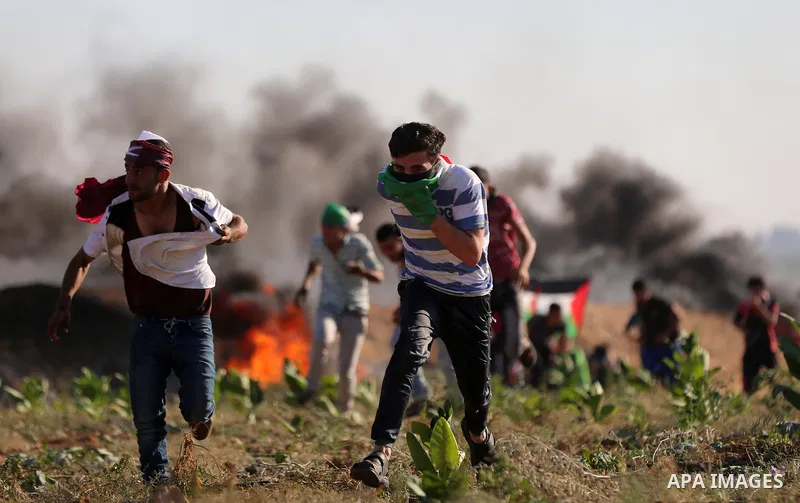 Palestinian protesters take cover during clashes with Israeli security forces following a demonstration against the blockade on the Gaza Strip, near the border fence east of Jabalia refugee camp on June 16, 2017. Photo b...