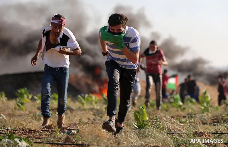 Palestinian protesters take cover during clashes with Israeli security forces following a demonstration against the blockade on the Gaza Strip, near the border fence east of Jabalia refugee camp on June 16, 2017. Photo b...