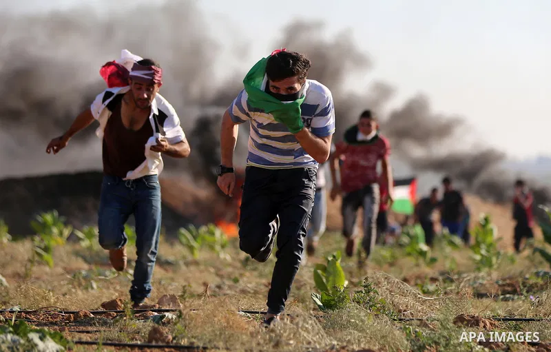 Palestinian protesters take cover during clashes with Israeli security forces following a demonstration against the blockade on the Gaza Strip, near the border fence east of Jabalia refugee camp on June 16, 2017. Photo b...