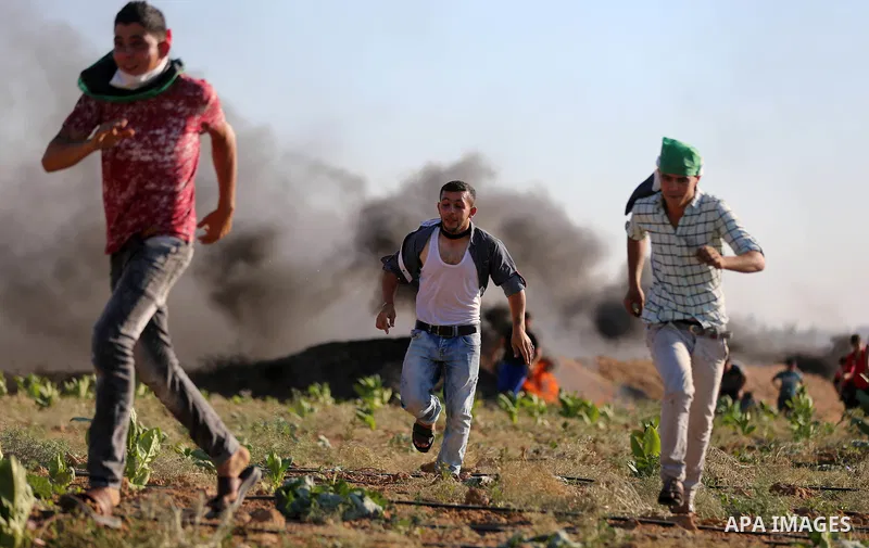 Palestinian protesters take cover during clashes with Israeli security forces following a demonstration against the blockade on the Gaza Strip, near the border fence east of Jabalia refugee camp on June 16, 2017. Photo b...