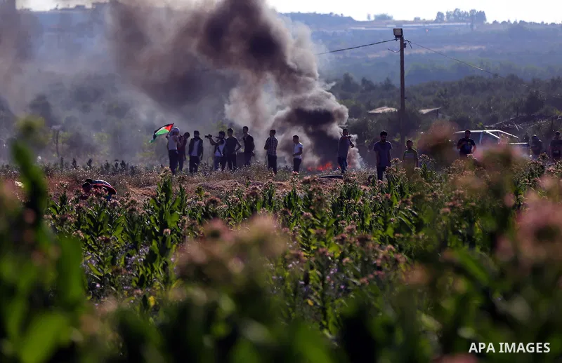 Palestinian protesters take cover during clashes with Israeli security forces following a demonstration against the blockade on the Gaza Strip, near the border fence east of Jabalia refugee camp on June 16, 2017. Photo b...