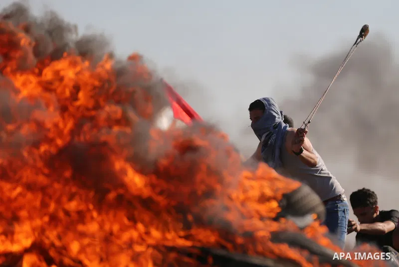 A Palestinian protester uses a slingshot to hurl stones towards Israeli security forces during clashes following a demonstration against the blockade on the Gaza Strip, near the border fence east of Jabalia refugee camp...