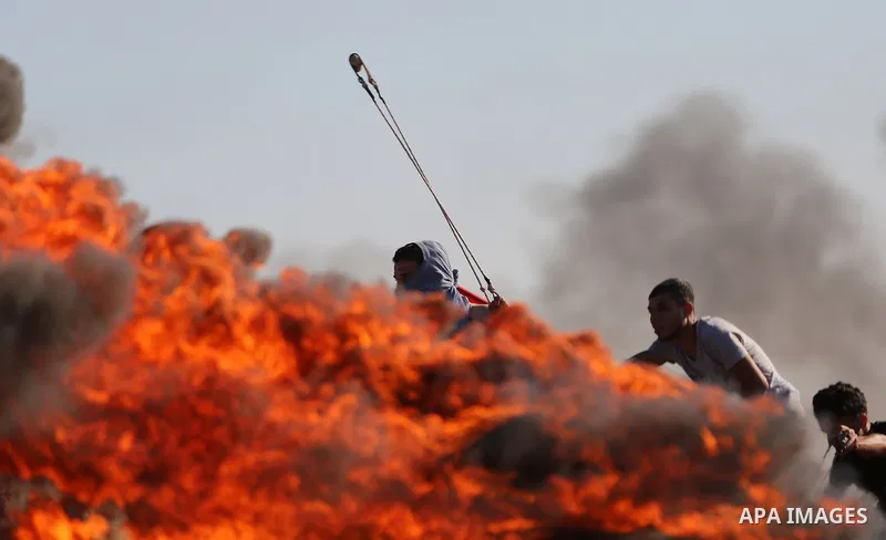 A Palestinian protester uses a slingshot to hurl stones towards Israeli security forces during clashes following a demonstration against the blockade on the Gaza Strip, near the border fence east of Jabalia refugee camp...