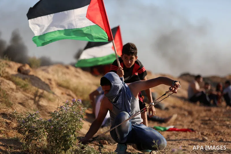 Palestinian protesters take cover during clashes with Israeli security forces following a demonstration against the blockade on the Gaza Strip, near the border fence east of Jabalia refugee camp on June 16, 2017. Photo b...