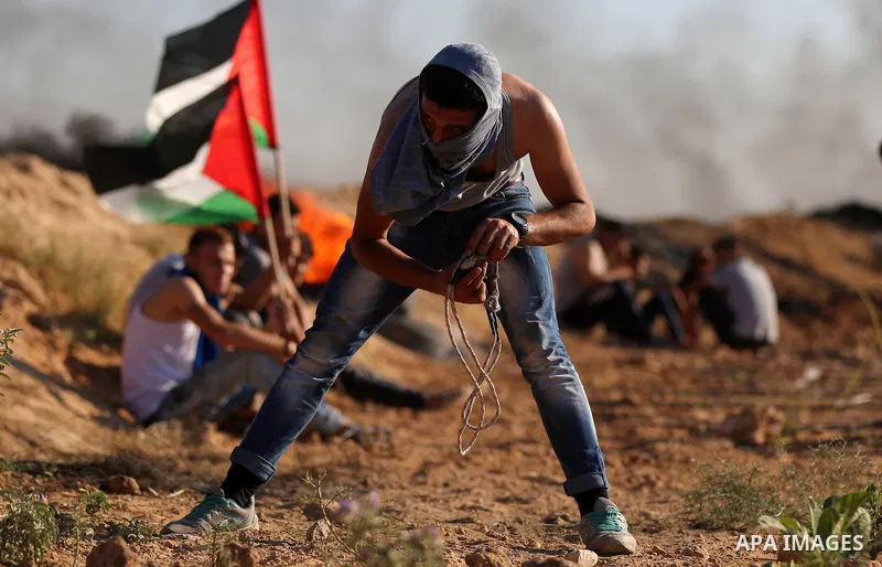 Palestinian protesters take cover during clashes with Israeli security forces following a demonstration against the blockade on the Gaza Strip, near the border fence east of Jabalia refugee camp on June 16, 2017. Photo b...