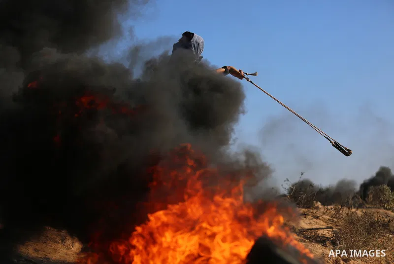 A Palestinian protester uses a slingshot to hurl stones towards Israeli security forces during clashes following a demonstration against the blockade on the Gaza Strip, near the border fence east of Jabalia refugee camp...