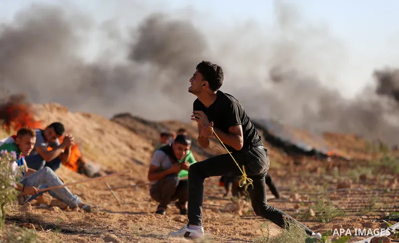 Palestinian protesters take cover during clashes with Israeli security forces following a demonstration against the blockade on the Gaza Strip, near the border fence east of Jabalia refugee camp on June 16, 2017. Photo b...