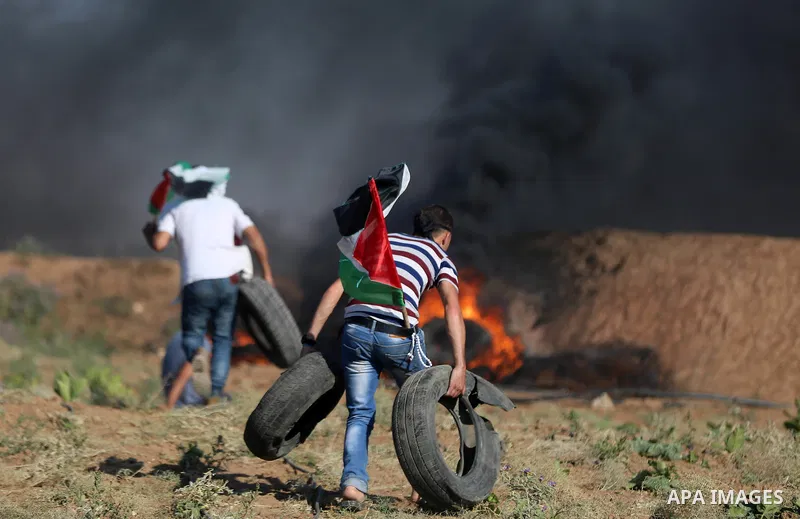 Palestinian protesters take cover during clashes with Israeli security forces following a demonstration against the blockade on the Gaza Strip, near the border fence east of Jabalia refugee camp on June 16, 2017. Photo b...