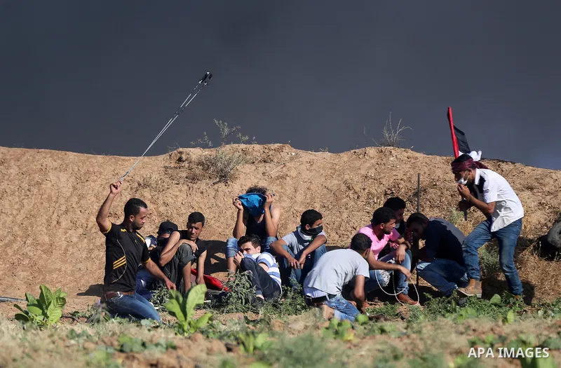 Palestinian protesters take cover during clashes with Israeli security forces following a demonstration against the blockade on the Gaza Strip, near the border fence east of Jabalia refugee camp on June 16, 2017. Photo b...