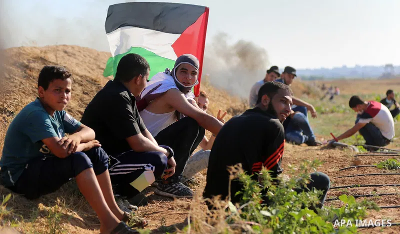 Palestinian protesters take cover during clashes with Israeli security forces following a demonstration against the blockade on the Gaza Strip, near the border fence east of Jabalia refugee camp on June 16, 2017. Photo b...