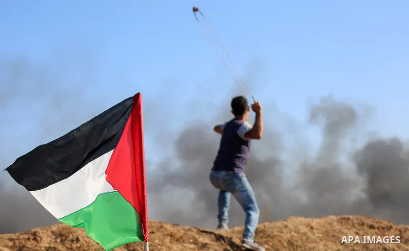 A Palestinian protester uses a slingshot to hurl stones towards Israeli security forces during clashes following a demonstration against the blockade on the Gaza Strip, near the border fence east of Jabalia refugee camp...