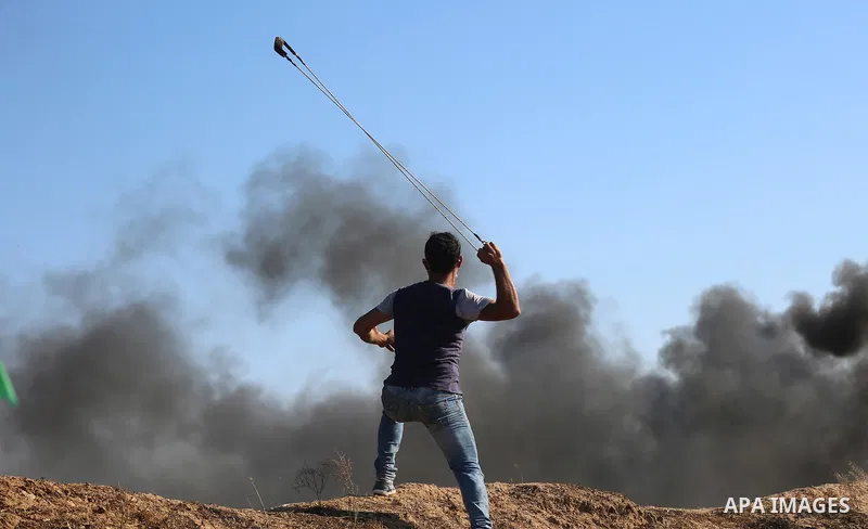 A Palestinian protester uses a slingshot to hurl stones towards Israeli security forces during clashes following a demonstration against the blockade on the Gaza Strip, near the border fence east of Jabalia refugee camp...