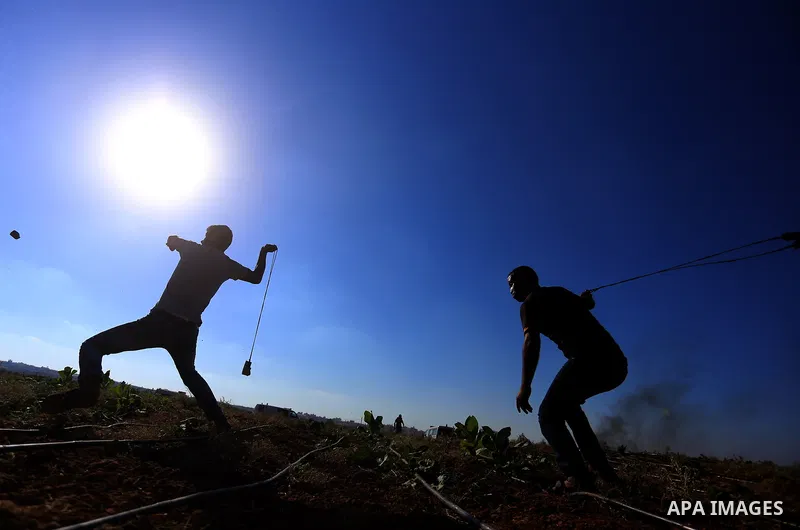 A Palestinian protester uses a slingshot to hurl stones towards Israeli security forces during clashes following a demonstration against the blockade on the Gaza Strip, near the border fence east of Jabalia refugee camp...