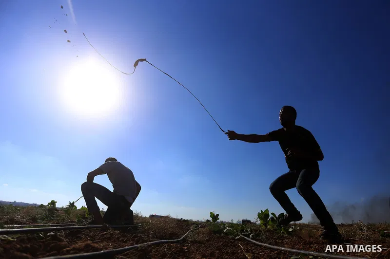 A Palestinian protester uses a slingshot to hurl stones towards Israeli security forces during clashes following a demonstration against the blockade on the Gaza Strip, near the border fence east of Jabalia refugee camp...