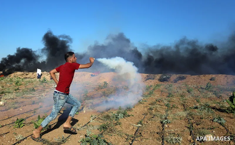 A Palestinian protester throws a tear gas canister towards Israeli security forces during clashes following a demonstration against the blockade on the Gaza Strip, near the border fence east of Jabalia refugee camp on Ju...
