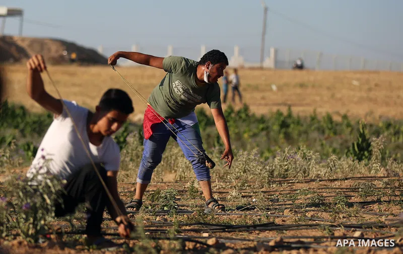 Palestinian protesters take cover during clashes with Israeli security forces following a demonstration against the blockade on the Gaza Strip, near the border fence east of Jabalia refugee camp on June 16, 2017. Photo b...
