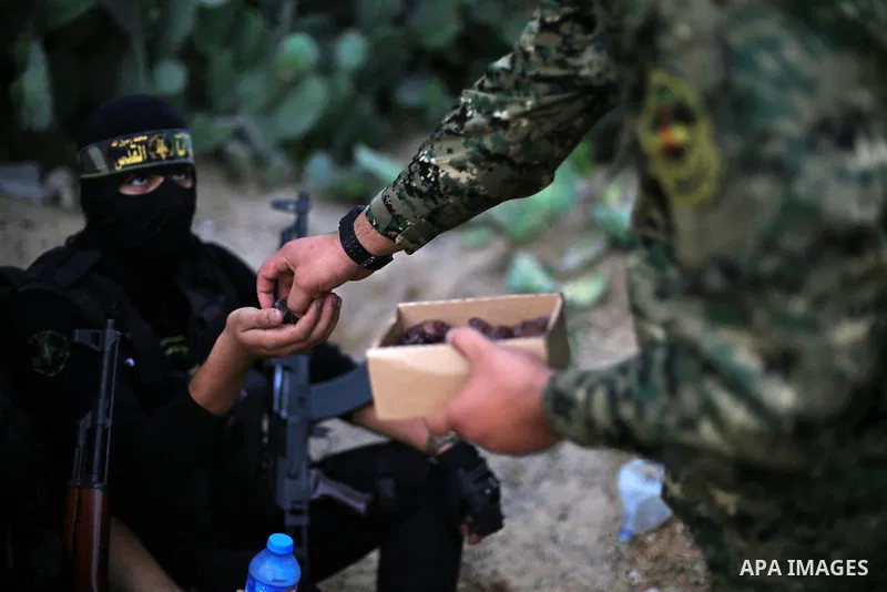 Palestinian militants from the Al-Quds Brigades, the armed wing of the Islamic Jihad movement break their fast as they guard the border between the Gaza Strip and Israel on the Muslim holy fasting month of Ramadan on Jun...