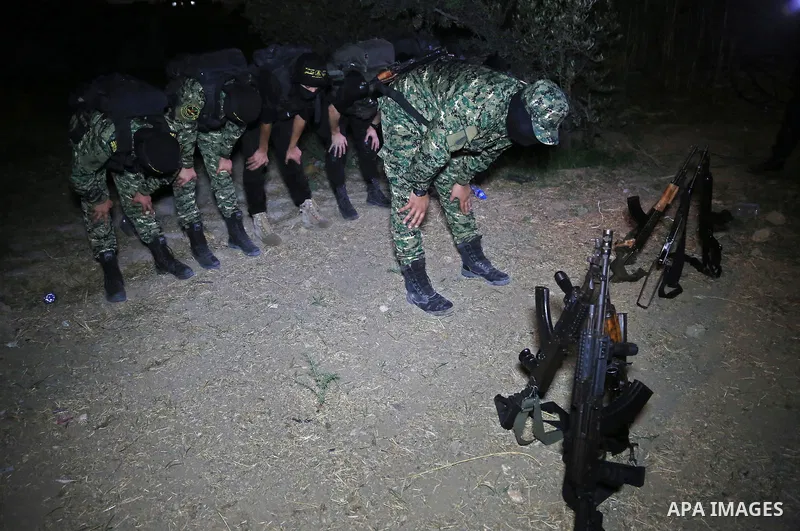 Palestinian militants from the Al-Quds Brigades, the armed wing of the Islamic Jihad movement perform prayer as they guard the border between the Gaza Strip and Israel on the Muslim holy fasting month of Ramadan on June...