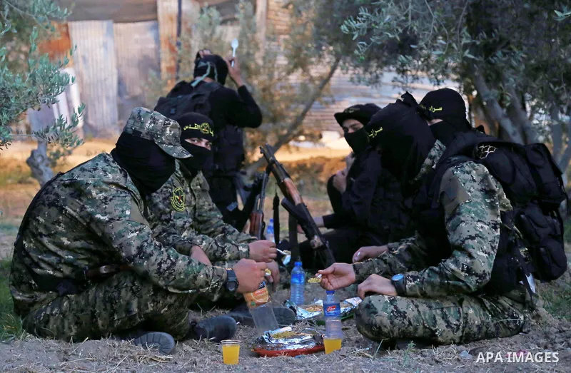 Palestinian militants from the Al-Quds Brigades, the armed wing of the Islamic Jihad movement break their fast as they guard the border between the Gaza Strip and Israel on the Muslim holy fasting month of Ramadan on Jun...