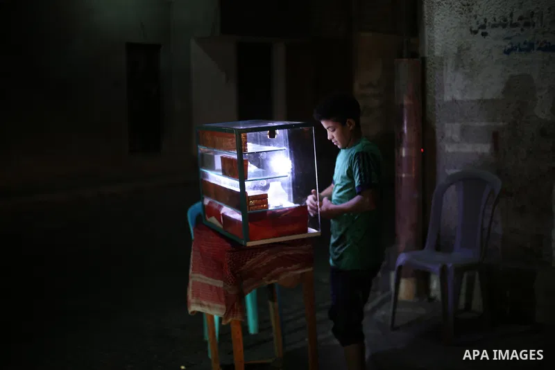 A Palestinian boy sells smoke during a power cut, outside his house at Al-Shate' refugee camp, in Gaza city on June 19, 2017. Photo by Mohammed Asad