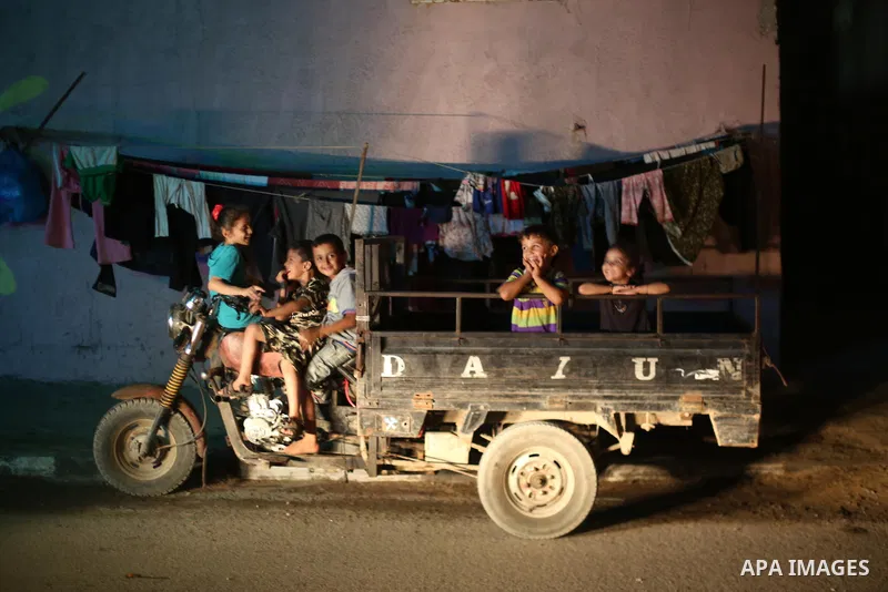 Palestinian children pose a photo during a power cut, outside their house at Al-Shate' refugee camp, in Gaza city on June 19, 2017. Photo by Mohammed Asad