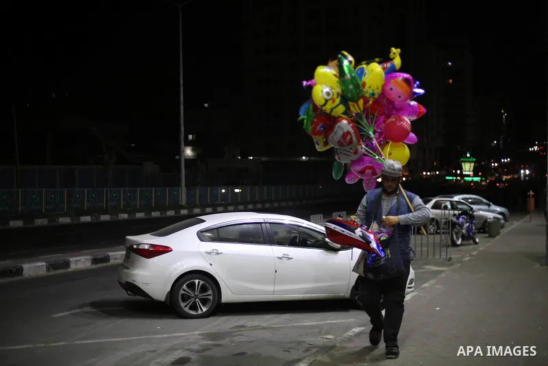 A Palestinian vendor sells balloons at the street during a power cut, in Gaza city on June 19, 2017. Photo by Mohammed Asad