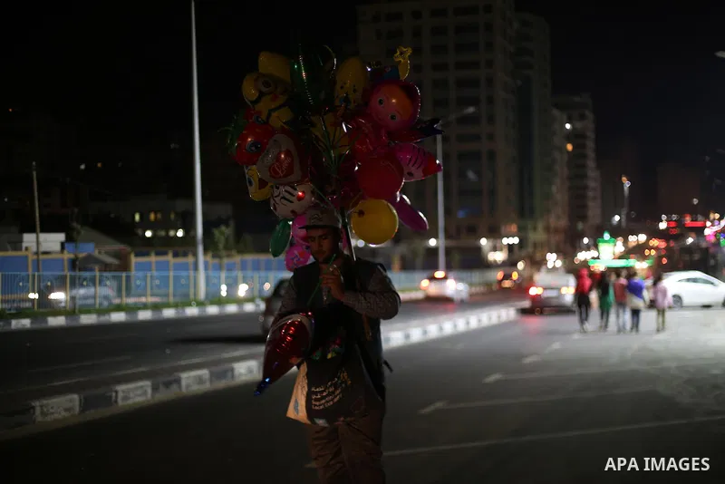 A Palestinian vendor sells balloons at the street during a power cut, in Gaza city on June 19, 2017. Photo by Mohammed Asad
