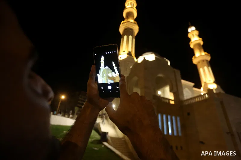 A Palestinian man takes photo to Mohammed Al Hassayna mosque as Palestinian laborers do construction work at night, on the Muslim holy fasting month of Ramadan, in Gaza city on June 20, 2017. Photo by Mohammed Asad
