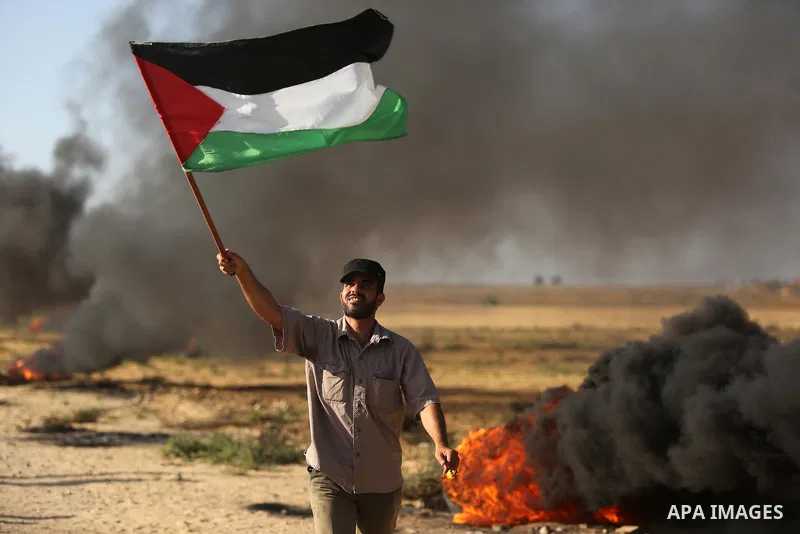 A protester holds a Palestinian flag during clashes with Israeli troops at a protest against reducing power supply to Gaza, near the border with Israel in Khan Younis in the southern Gaza Strip June 20, 2017. Photo by As...