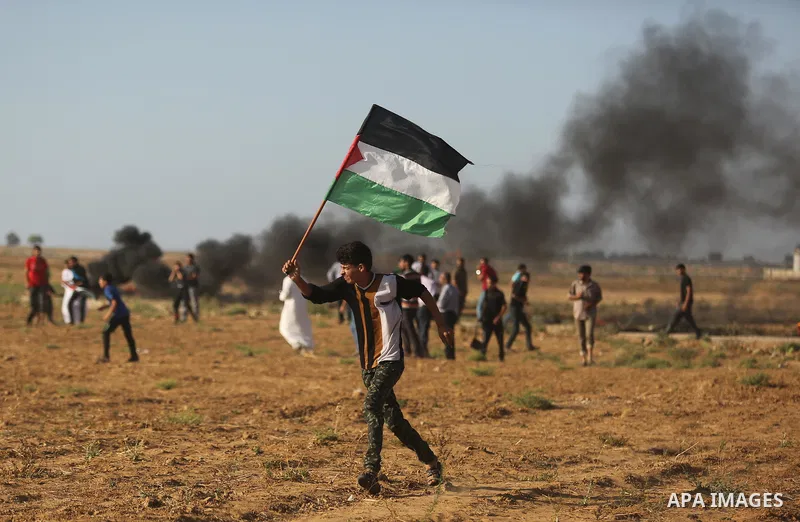 A protester holds a Palestinian flag during clashes with Israeli troops at a protest against reducing power supply to Gaza, near the border with Israel in Khan Younis in the southern Gaza Strip June 20, 2017. Photo by As...