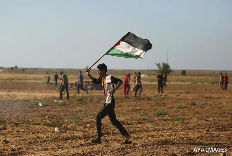 A protester holds a Palestinian flag during clashes with Israeli troops at a protest against reducing power supply to Gaza, near the border with Israel in Khan Younis in the southern Gaza Strip June 20, 2017. Photo by As...