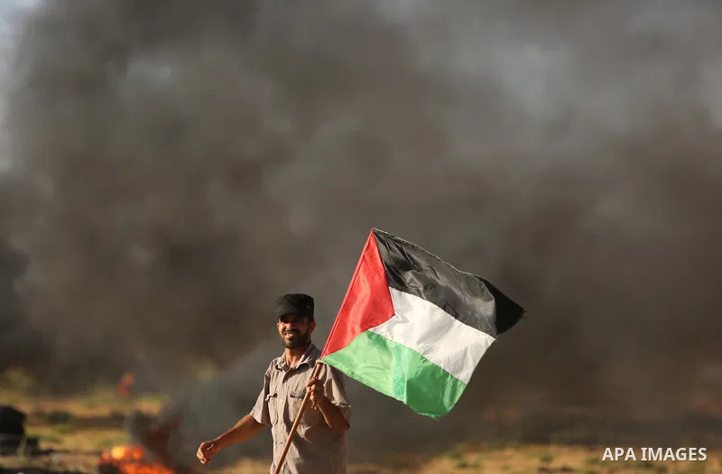 A protester holds a Palestinian flag during clashes with Israeli troops at a protest against reducing power supply to Gaza, near the border with Israel in Khan Younis in the southern Gaza Strip June 20, 2017. Photo by As...