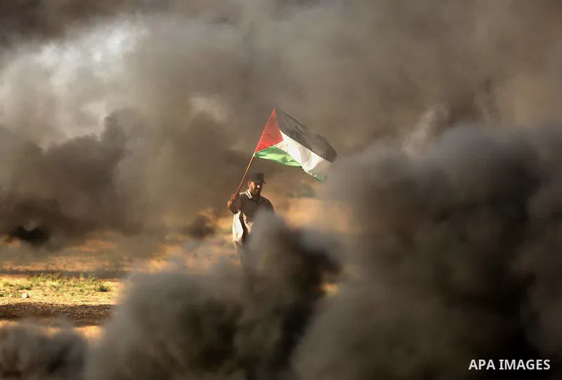 A protester holds a Palestinian flag during clashes with Israeli troops at a protest against reducing power supply to Gaza, near the border with Israel in Khan Younis in the southern Gaza Strip June 20, 2017. Photo by As...