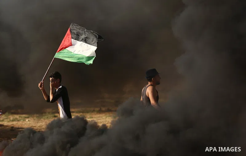 A protester holds a Palestinian flag during clashes with Israeli troops at a protest against reducing power supply to Gaza, near the border with Israel in Khan Younis in the southern Gaza Strip June 20, 2017. Photo by As...