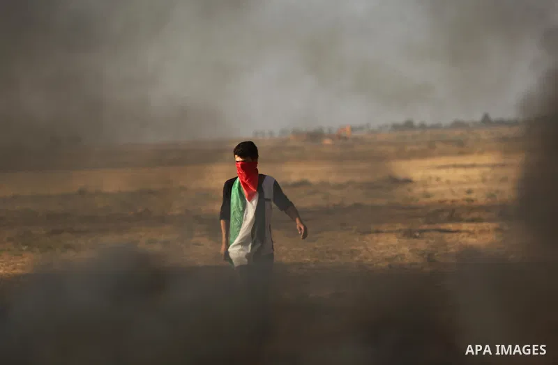 A protester holds a Palestinian flag during clashes with Israeli troops at a protest against reducing power supply to Gaza, near the border with Israel in Khan Younis in the southern Gaza Strip June 20, 2017. Photo by As...