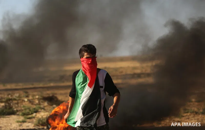 A protester covers his face with a Palestinian flag during clashes with Israeli troops at a protest against reducing power supply to Gaza, near the border with Israel in Khan Younis in the southern Gaza Strip June 20, 20...