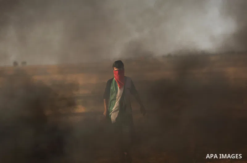 A protester holds a Palestinian flag during clashes with Israeli troops at a protest against reducing power supply to Gaza, near the border with Israel in Khan Younis in the southern Gaza Strip June 20, 2017. Photo by As...