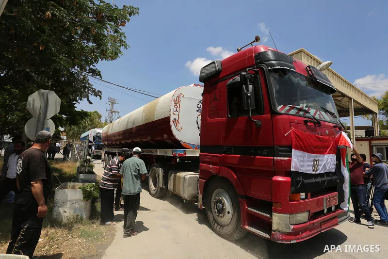 A Palestinian man puts the national flag and Egyptian flag on an Egyptian truck carrying fuel after it was enter the southern Gaza Strip from Egypt through the Rafah border crossing on June 21, 2017. Egypt began to deliv...