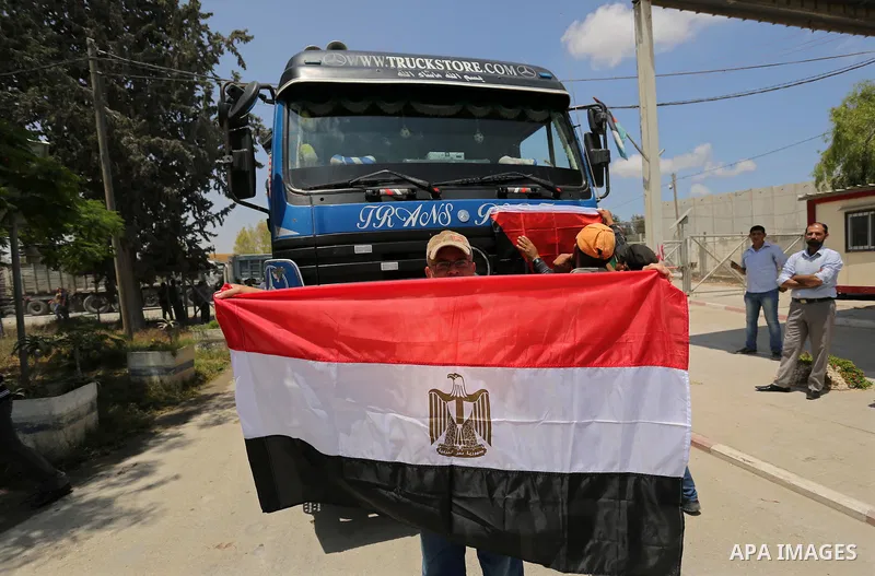 A Palestinian man holds an Egyptian flag in front of Egyptian truck carrying fuel after entering the southern Gaza Strip from Egypt through the Rafah border crossing on June 21, 2017. Egypt began to deliver a million lit...