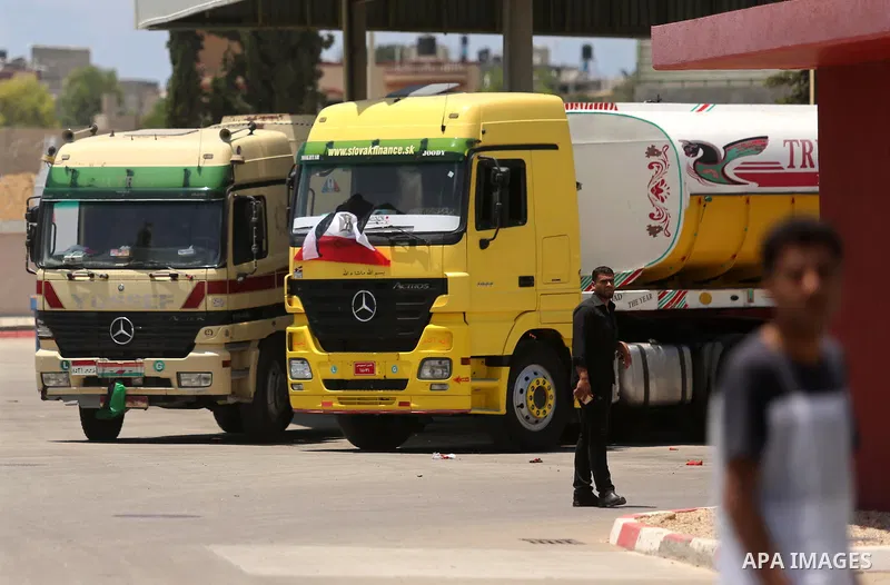 Palestinians walk as Egyptian trucks carrying fuel arrive to Gaza's power plant in Nusseirat, in the central Gaza Strip after entering the southern Gaza Strip from Egypt through the Rafah border crossing on June 21, 2017...