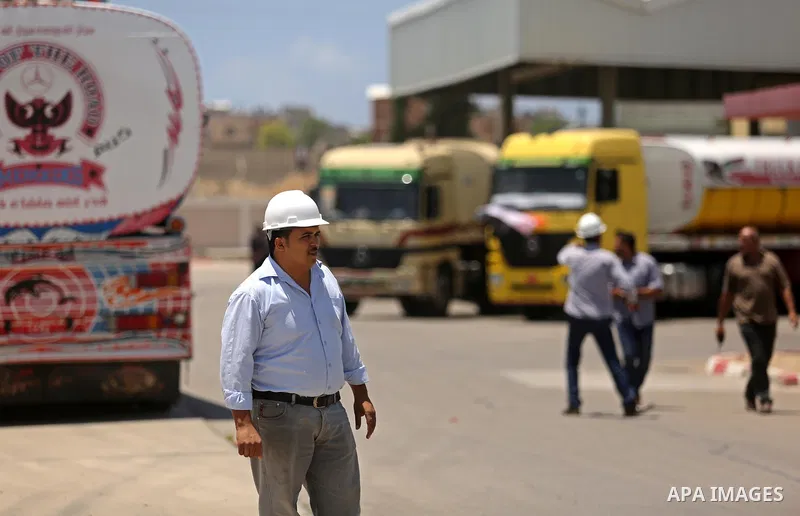 Palestinians walk as Egyptian trucks carrying fuel arrive to Gaza's power plant in Nusseirat, in the central Gaza Strip after entering the southern Gaza Strip from Egypt through the Rafah border crossing on June 21, 2017...