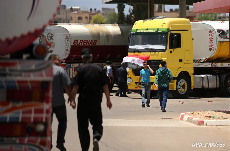 Palestinians walk as Egyptian trucks carrying fuel arrive to Gaza's power plant in Nusseirat, in the central Gaza Strip after entering the southern Gaza Strip from Egypt through the Rafah border crossing on June 21, 2017...