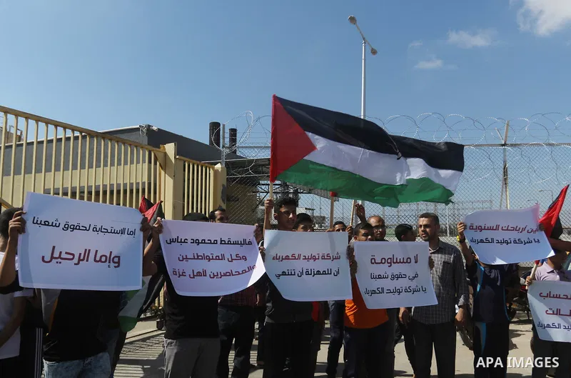 Palestinians hold banners during a protest against the worsening crisis of power outages in front of Gaza's power plant in Nuseirat in the center of Gaza strip, on June 21, 2017. Egypt began to deliver a million litres o...