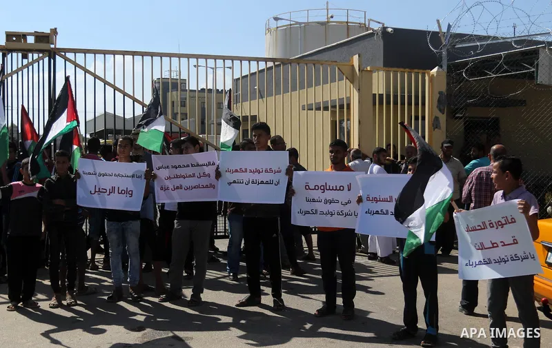 Palestinians hold banners during a protest against the worsening crisis of power outages in front of Gaza's power plant in Nuseirat in the center of Gaza strip, on June 21, 2017. Egypt began to deliver a million litres o...