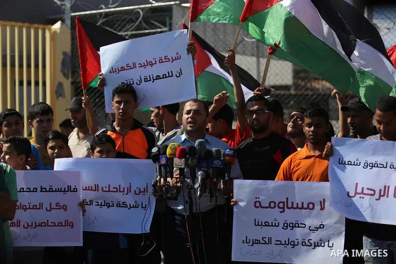 Palestinians hold banners during a protest against the worsening crisis of power outages in front of Gaza's power plant in Nuseirat in the center of Gaza strip, on June 21, 2017. Egypt began to deliver a million litres o...