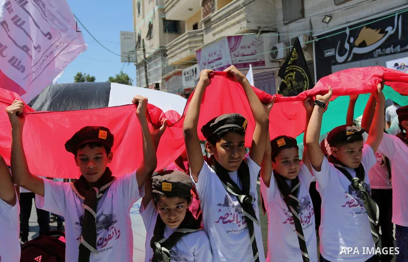 Palestinian Scout youths wave a large Palestinian flag in a protest marking the annual al-Quds Day, or Jerusalem Day, following Friday prayer in Gaza city June 23, 2017. Photo by Ashraf Amra