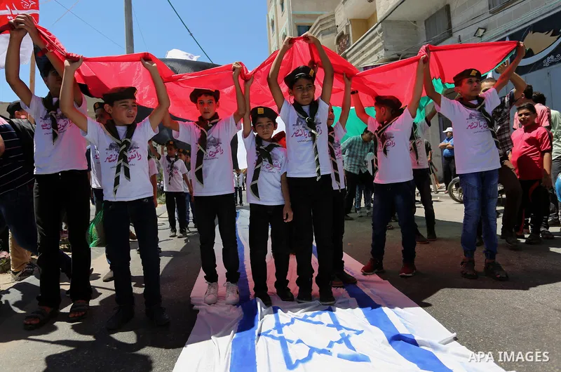 Palestinian Scout youths wave a large Palestinian flag and step on the Israeli flag in a protest marking the annual al-Quds Day, or Jerusalem Day, following Friday prayer in Gaza city June 23, 2017. Photo by Ashraf Amra