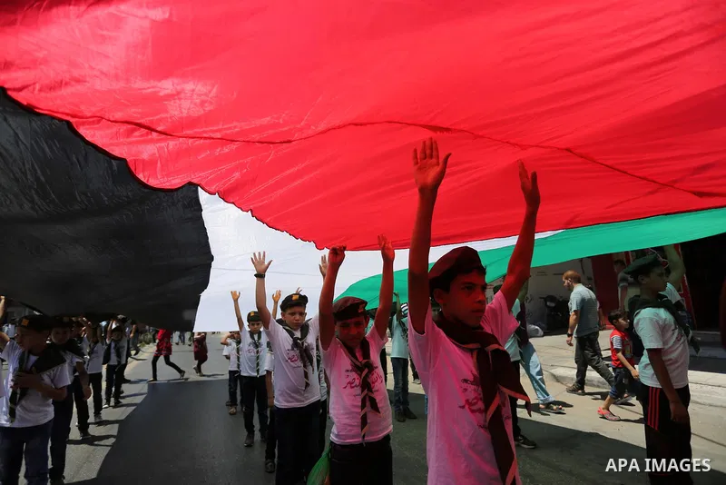 Palestinian Scout youths wave a large Palestinian flag in a protest marking the annual al-Quds Day, or Jerusalem Day, following Friday prayer in Gaza city June 23, 2017. Photo by Ashraf Amra
