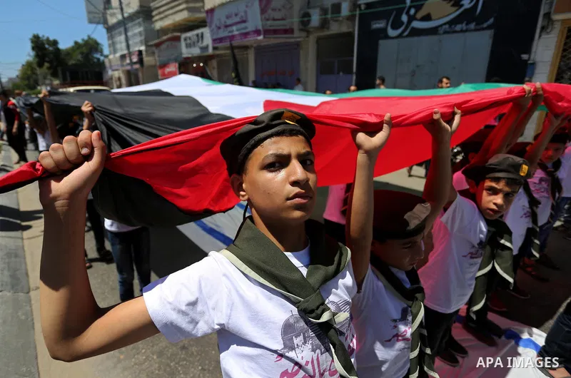 Palestinian Scout youths wave a large Palestinian flag in a protest marking the annual al-Quds Day, or Jerusalem Day, following Friday prayer in Gaza city June 23, 2017. Photo by Ashraf Amra