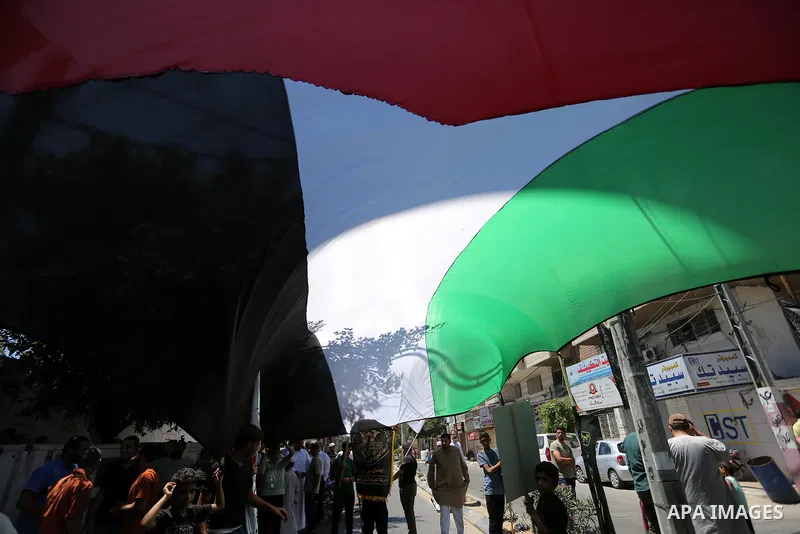 Palestinians wave a large Palestinian flag in a protest marking the annual al-Quds Day, or Jerusalem Day, following Friday prayer in Gaza city June 23, 2017. Photo by Ashraf Amra